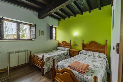 two beds in a room with green walls and wooden floors at Cortijo las monjas in Villaescusa de las Torres