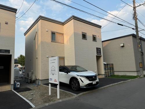 a white car parked in front of a house at Nomad Stay Chitose in Chitose