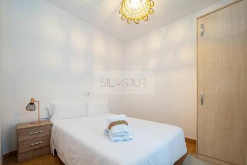 a white bedroom with a white bed and a chandelier at Vive Oviedo 3 By Silastur in Oviedo