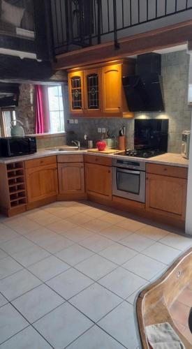 - une cuisine avec des placards en bois et une cuisinière dans l'établissement Gîte de la Guinchère Bretagne, à Saint-Georges-de-Reintembault