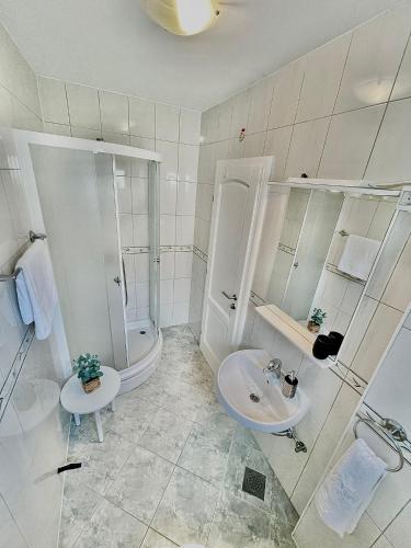 a white bathroom with a sink and a shower at Apartments Katara in Brela