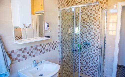 a bathroom with a sink and a glass shower at Apartment Luminos in Mostar