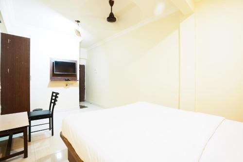 a bedroom with a bed and a table and a tv at Hotel Della Comfort near Ambreshwar Shiv Mandir, Ambernath in Ambernath
