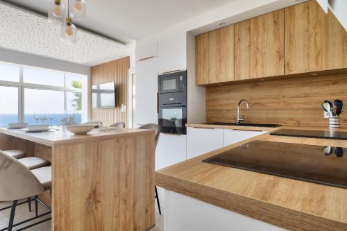 une cuisine avec des armoires en bois et un comptoir dans l'établissement Vue mer - Séjour à deux pas de la plage, à La Barre-de-Monts