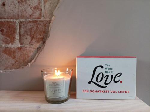 a candle sitting on a table next to a box at Waterval Wellness-suite met Sauna! in Bodegraven