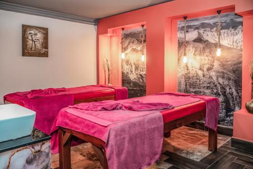 two beds in a room with pink walls at Royal Wings Hotel in Lara