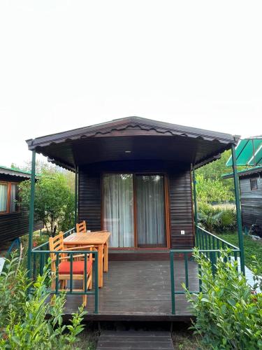 a cabin with a wooden deck with a table and chairs at Olympos Yavuz Hotel in Cıralı