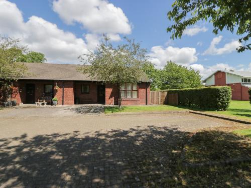 a red brick house with a tree in the driveway at 21 Eamont Park in Penrith