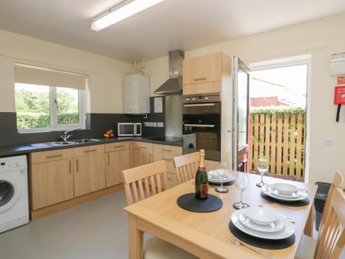 a kitchen with a wooden table with a bottle of wine at 21 Eamont Park in Penrith