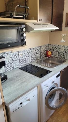 une cuisine avec un lave-linge et un micro-ondes dans l'établissement Résidence VILLAS DU LAC, à Soustons