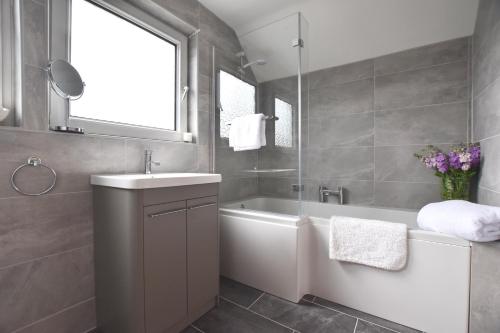 ein Badezimmer mit Badewanne, Waschbecken und Spiegel in der Unterkunft Greenfields in St. Davids