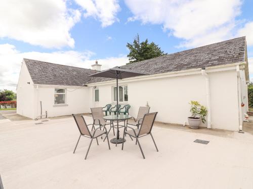 a patio with a table with chairs and an umbrella at White Cottage in Abbeyfeale
