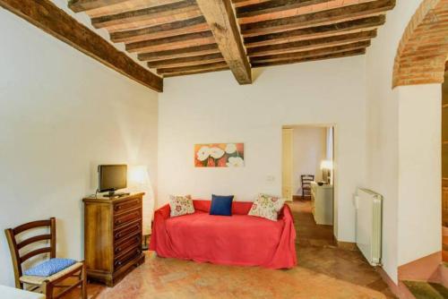a bedroom with a red bed and a tv at Case dei Fiori Residenza Storica in Torrita di Siena