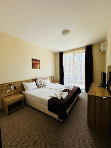 a hotel room with a large bed and a television at Ivian Family Hotel in Ravda