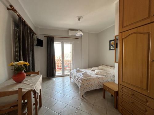 a bedroom with a bed and a table and a window at Brati II Beach Hotel in Arkoudi