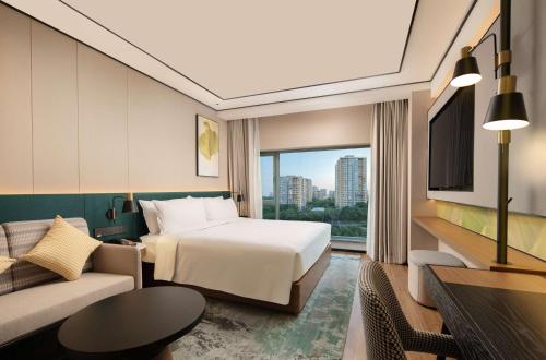 a hotel room with a bed and a couch at Hilton Garden Inn Beijing West Railway Station in Beijing