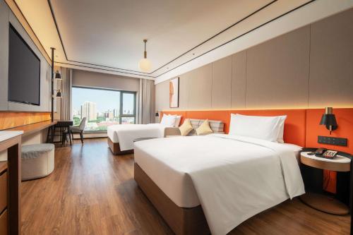 a hotel room with two beds and a flat screen tv at Hilton Garden Inn Beijing West Railway Station in Beijing