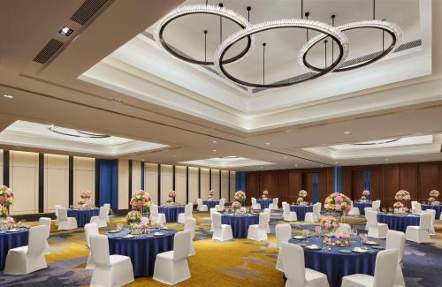 a ballroom with tables and chairs and a chandelier at Hyatt Centric Hebbal Bengaluru in Bengaluru