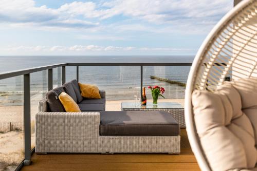 a balcony with two chairs and a table and the beach at Apartament Dream View Gardenia Front in Dziwnów