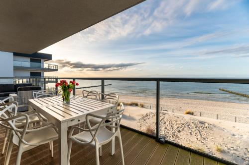 a table and chairs on a balcony with a view of the beach at Apartament Dream View Gardenia Front in Dziwnów