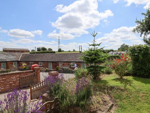 a garden with purple flowers in front of a building at The Hay Barn in Chester
