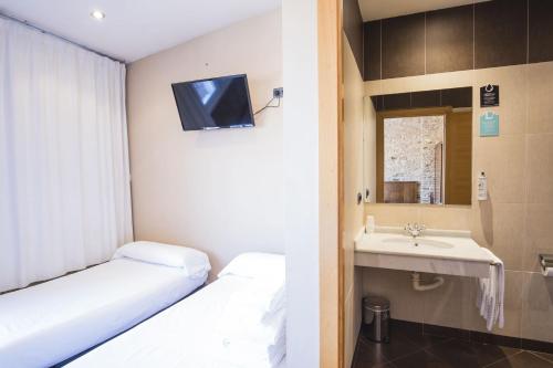 Una pequeña habitación con una cama y un lavabo. en Hotel Alda Avenida, en Santiago de Compostela