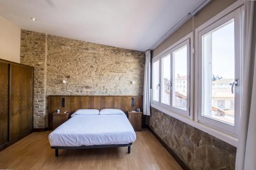 Un dormitorio con una cama y dos ventanas. en Hotel Alda Avenida, en Santiago de Compostela
