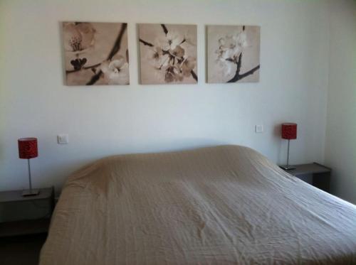 une chambre avec un lit avec trois tableaux au mur dans l'établissement Rez de villa, vue panoramique mer et montagne !, à Vico