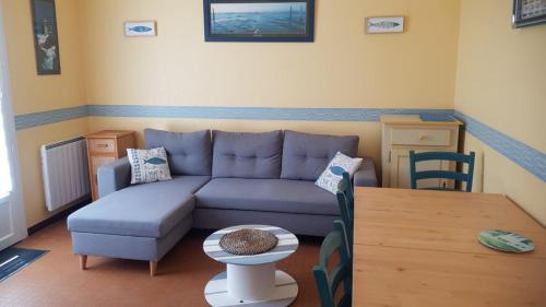 un salon avec un canapé bleu et une table dans l'établissement Maison Madoret 6 personnes, à Saint-Hilaire-de-Riez