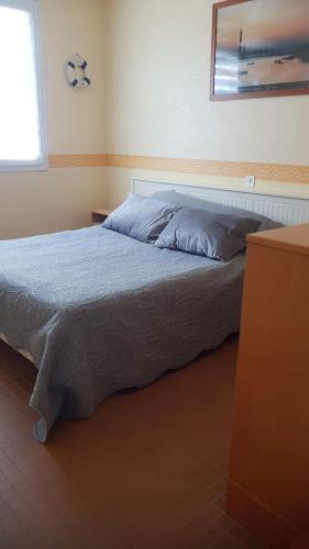 une chambre avec un lit avec une couverture bleue et une fenêtre dans l'établissement Maison Madoret 6 personnes, à Saint-Hilaire-de-Riez