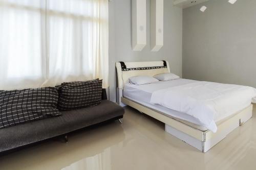 a white bedroom with a bed and a couch at RedDoorz at Jalan Ujung Sampun Berastagi in Berastagi