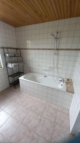 La salle de bains est pourvue d'une baignoire et d'une douche. dans l'établissement Gîte de la ferme d'Hougerville, à Colleville