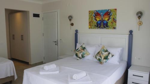 a white bed with two pillows and a painting on the wall at Cemile Hanım Konağı in Cesme
