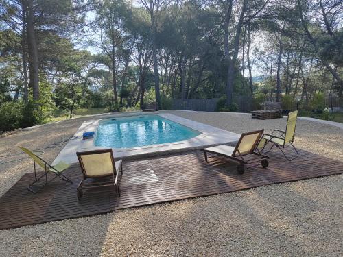 - une piscine avec 2 chaises sur une terrasse en bois dans l'établissement Le Clos Zinou, à Lambesc