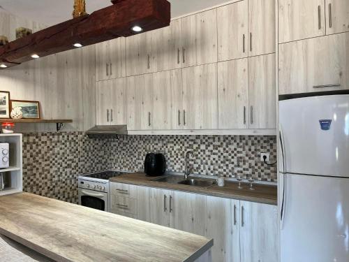 a kitchen with wooden cabinets and a white refrigerator at Eleni's country house in Karpathos Town