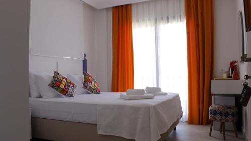 a bedroom with a bed with white sheets and orange curtains at Cemile Hanım Konağı in Cesme