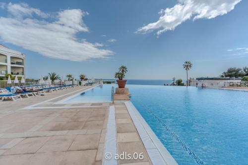 une piscine dans un complexe hôtelier avec des palmiers dans l'établissement Un Studio de Charme Vue Mer & Piscine d'Exception, à Cannes