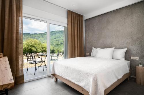 a bedroom with a bed and a large window at Gefiri Plakas Hotel, Tzoumerka in Plaka
