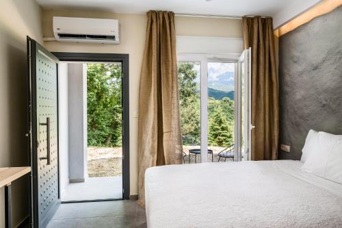 a bedroom with a bed and a large window at Gefiri Plakas Hotel, Tzoumerka in Plaka