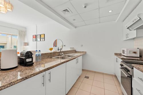 a kitchen with white cabinets and a counter top at Charming 1BR in The Greens, Near Metro in Dubai