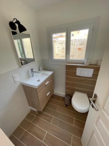 een badkamer met een toilet, een wastafel en een spiegel bij Maisonnette avec terrasse et patio à Cassis in Cassis
