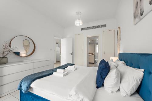 a white and blue bedroom with a blue couch at Charming 1BR in The Greens, Near Metro in Dubai