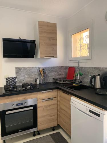 Il comprend une cuisine équipée d'une cuisinière. four supérieur à côté d'un évier dans l'établissement Maison indépendante terasse et jardin, à Nîmes