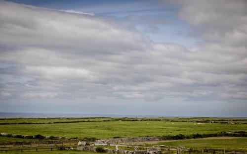 a green field with a fence and a cloudy sky at Cahermaclanchy House in Doolin