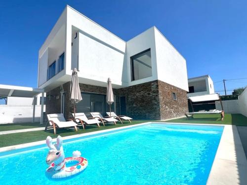 a house with a swimming pool with a toy rabbit in the water at Casa Charli Lisboa-Piscine chauffée en option in Aroeira
