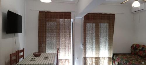 a room with two windows with a table and a chair at beach apartment in Pefkohori