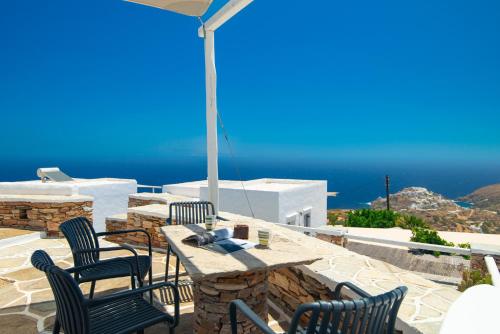 a patio with a table and chairs and the ocean at Windmill Bella Vista in Artemonas