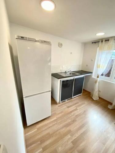 Il comprend une cuisine équipée d'un réfrigérateur blanc et du parquet. dans l'établissement Charmante maison à Clermont avec terrasse proche de Paris, à Clermont