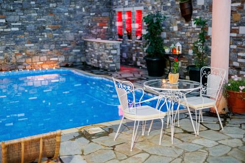 a table and chairs next to a swimming pool at Palladio Hotel - Portaria in Portaria