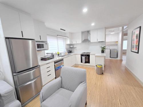 a kitchen with a refrigerator and a chair in it at 10 Angels in Christchurch